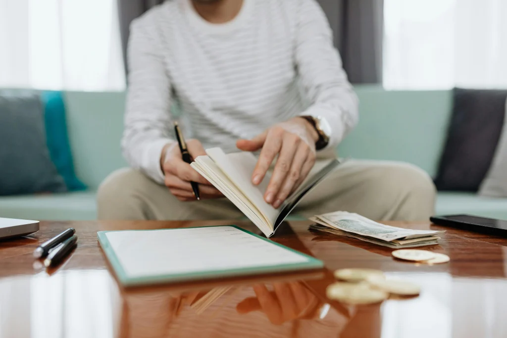 Person reviewing a garden journal or seed catalog indoors near a rainy window
