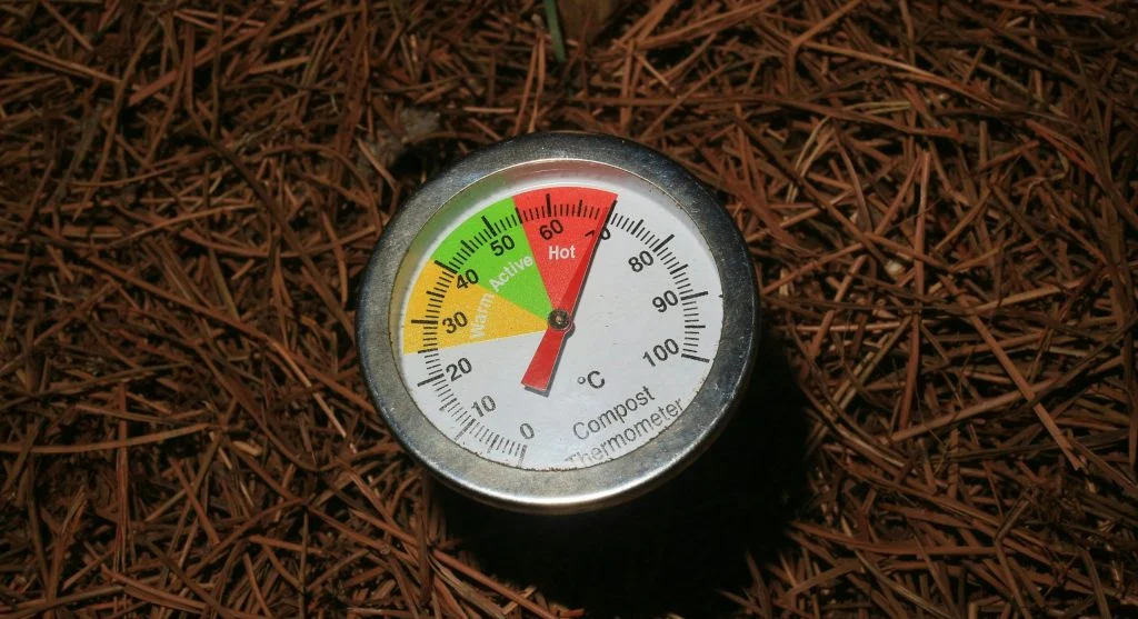Close-up of a compost thermometer in soil, temperature in active range