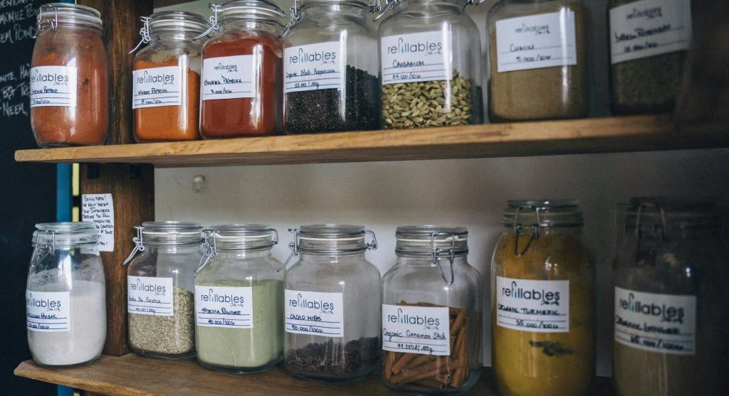 Seeds stored in labeled glass jars with silica gel packets inside a refrigerator