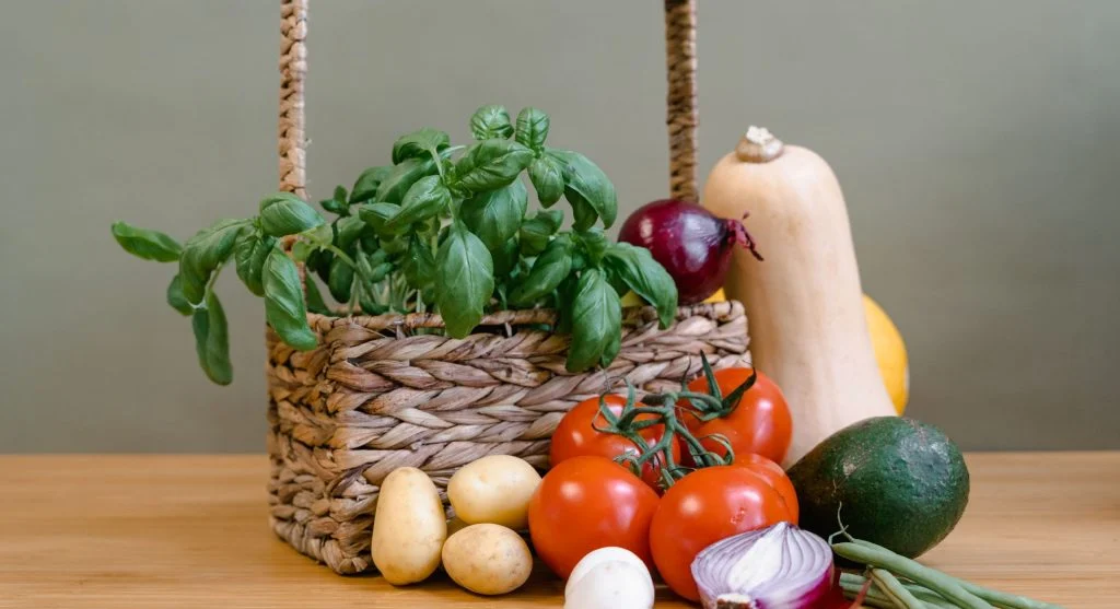 Basket of easy beginner vegetables — cherry tomatoes, beans, zucchini, herbs