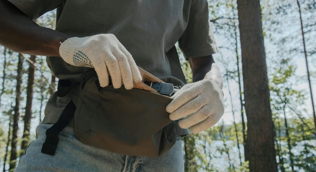Gardener wearing full protective gloves and clothing while working near a wooded area