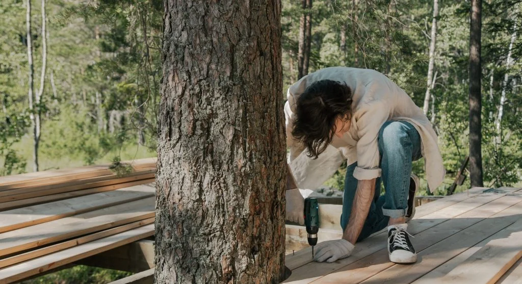 Person building a simple 4x4 raised bed frame from lumber in a backyard